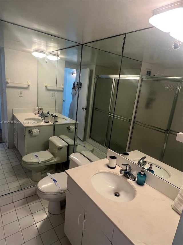 bathroom featuring oversized vanity, toilet, tile floors, and a shower with shower door