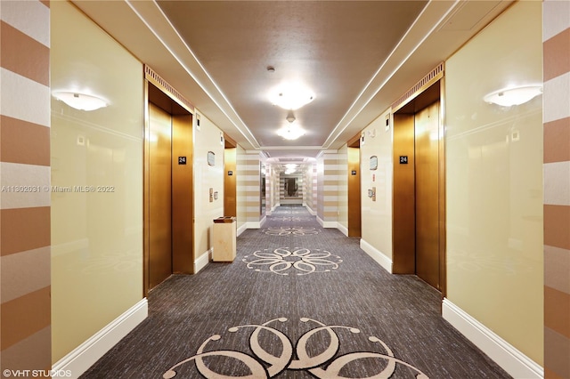 hallway with dark carpet and elevator