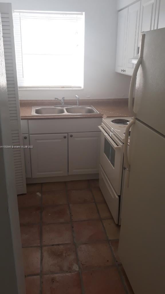 kitchen with white cabinets, a healthy amount of sunlight, white appliances, and sink