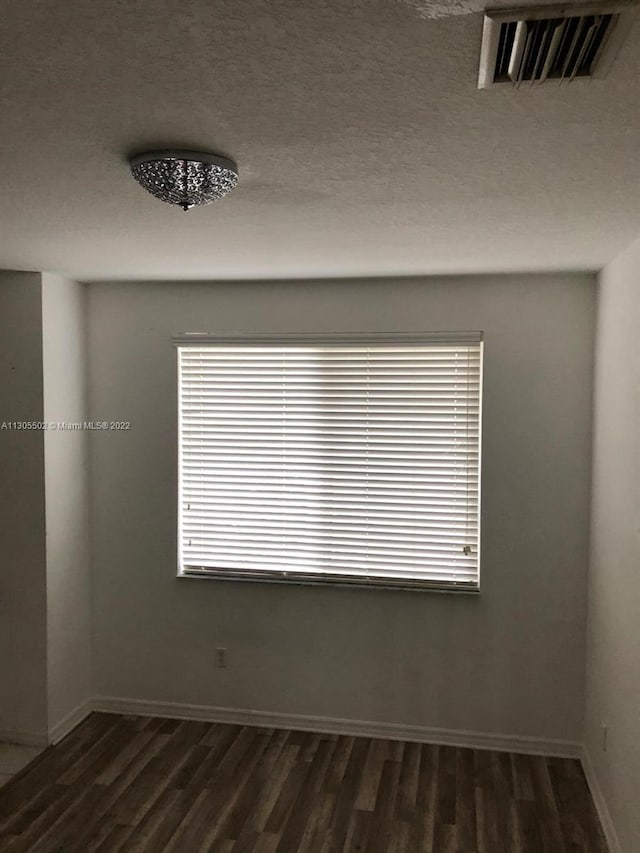 unfurnished room with a textured ceiling and dark wood-type flooring