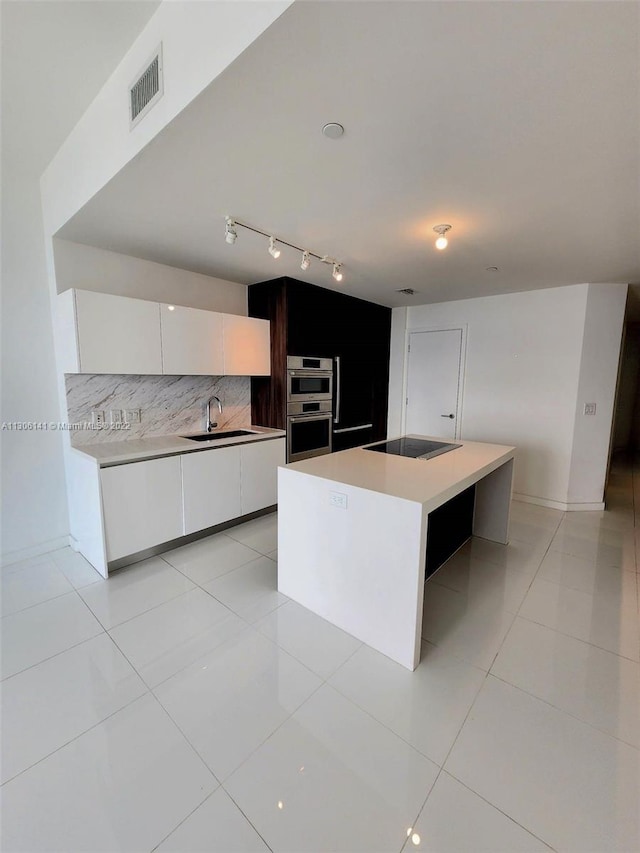 kitchen featuring light tile floors, a kitchen island, stainless steel double oven, white cabinets, and tasteful backsplash