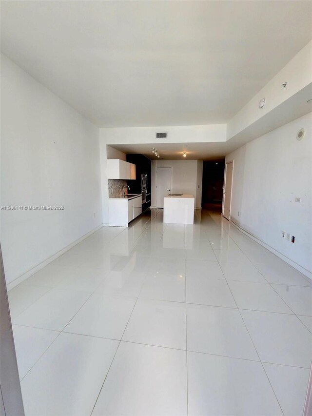 empty room featuring light tile floors and sink