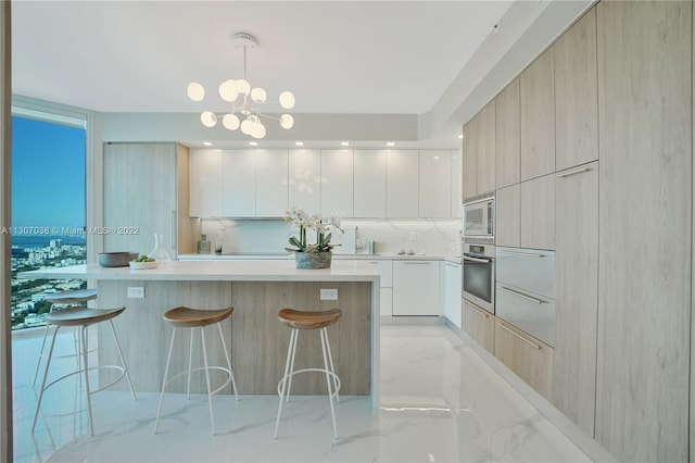 kitchen featuring a kitchen island, a kitchen breakfast bar, white cabinets, appliances with stainless steel finishes, and an inviting chandelier