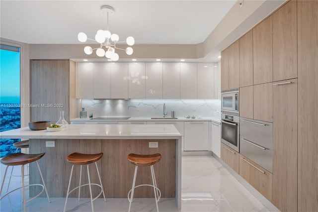 kitchen featuring pendant lighting, stainless steel appliances, a kitchen island, white cabinetry, and an inviting chandelier