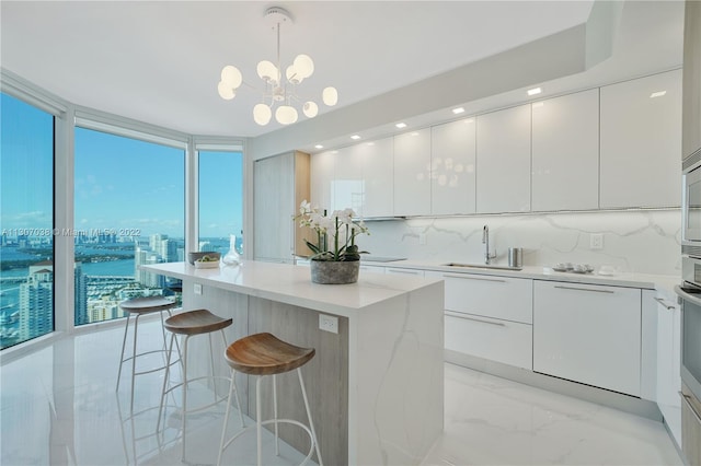 kitchen with a kitchen island, hanging light fixtures, white cabinets, and a chandelier