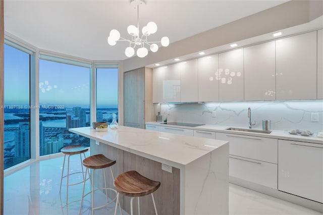 kitchen with decorative light fixtures, an inviting chandelier, white cabinetry, sink, and light stone counters