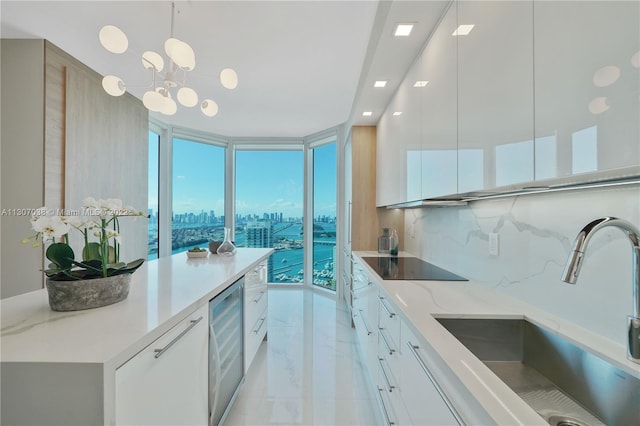 kitchen with white cabinets, a chandelier, black electric cooktop, light tile flooring, and wine cooler