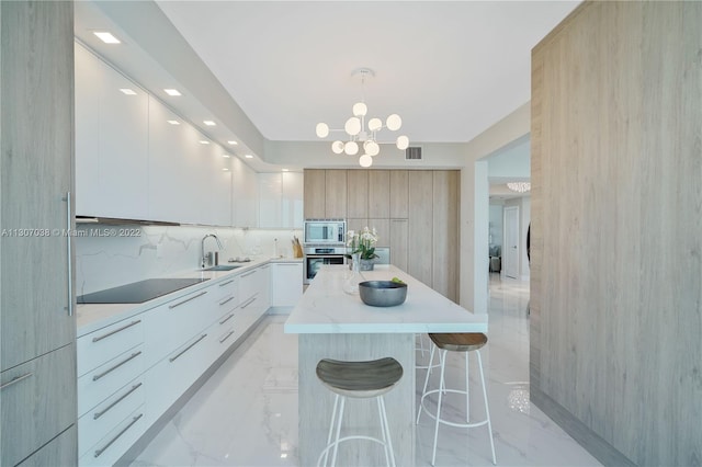 kitchen featuring a notable chandelier, appliances with stainless steel finishes, light tile floors, a kitchen island, and tasteful backsplash