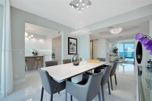 dining space with light tile floors, an inviting chandelier, and a tray ceiling