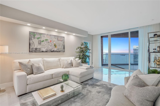 tiled living room featuring a water view and floor to ceiling windows