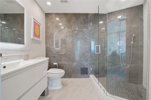 bathroom with vanity, tile walls, tile floors, a shower with door, and toilet