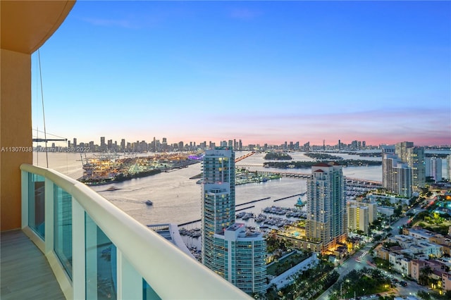 balcony at dusk featuring a water view