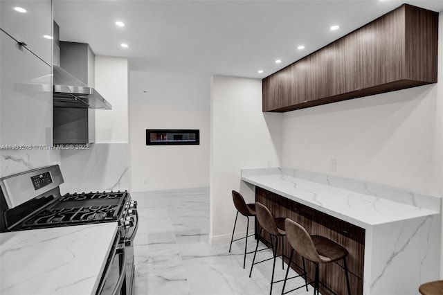 kitchen with gas stove, a kitchen breakfast bar, light tile flooring, and light stone countertops