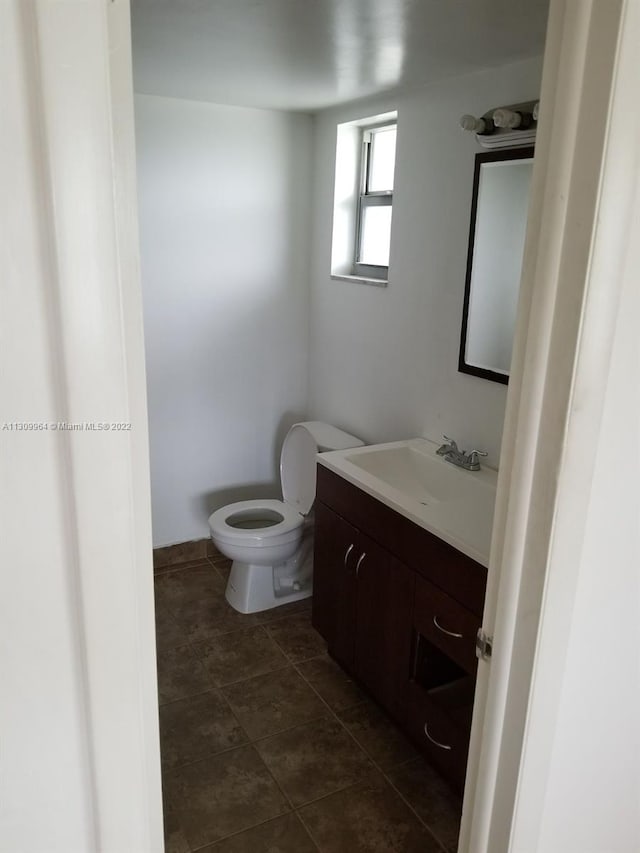 bathroom with toilet, tile flooring, and vanity