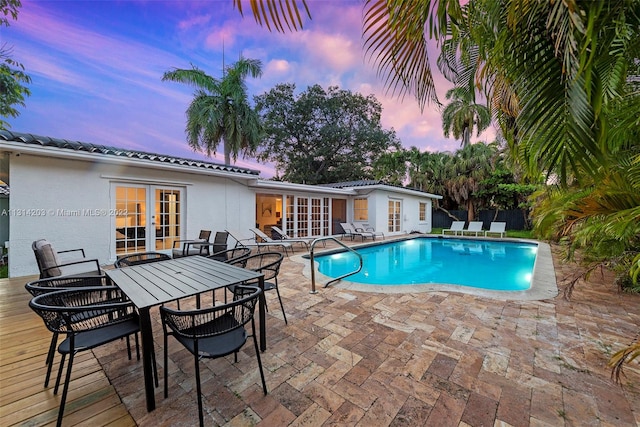 pool at dusk with a patio and french doors