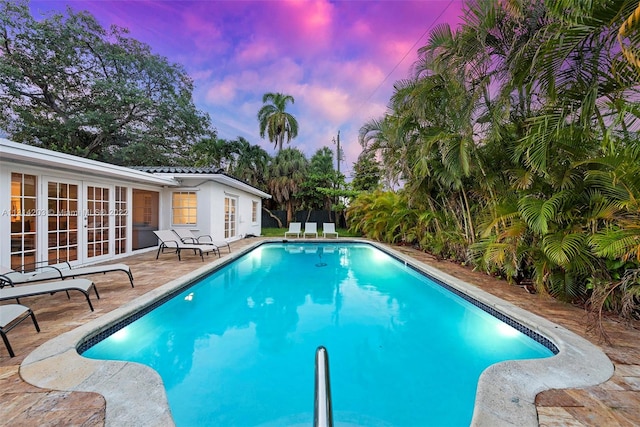 pool at dusk with a patio area