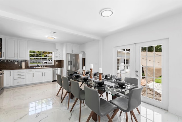 tiled dining space with french doors, sink, and a wealth of natural light