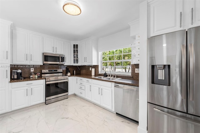 kitchen featuring sink, light tile floors, backsplash, stainless steel appliances, and white cabinetry