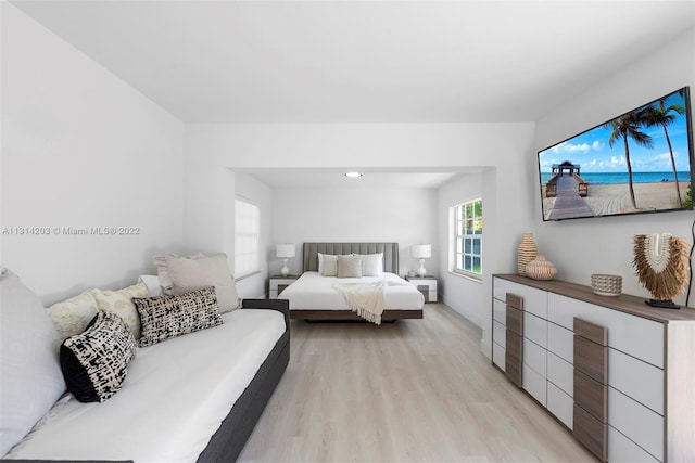 bedroom with light hardwood / wood-style floors and a water view