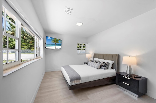 bedroom with light hardwood / wood-style floors and multiple windows