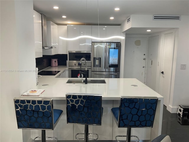 kitchen featuring a kitchen bar, kitchen peninsula, stainless steel appliances, and white cabinetry