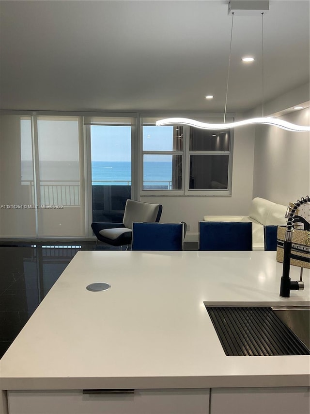 kitchen with a water view, hanging light fixtures, and sink