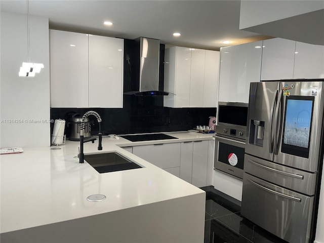 kitchen with white cabinets, appliances with stainless steel finishes, and wall chimney range hood