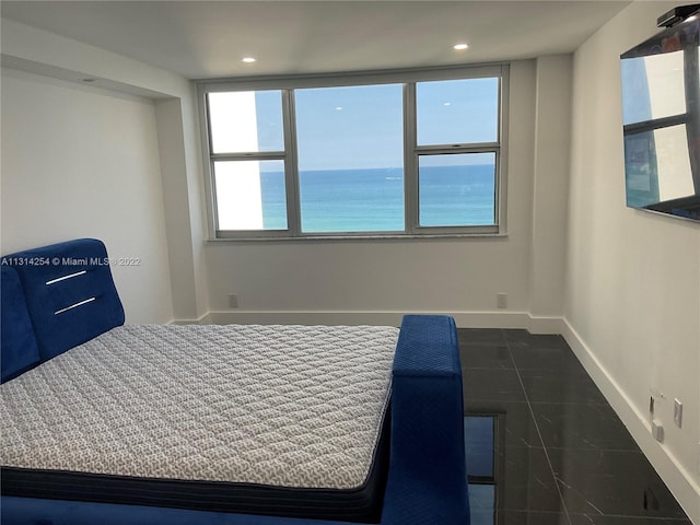 unfurnished bedroom with a water view and dark tile floors