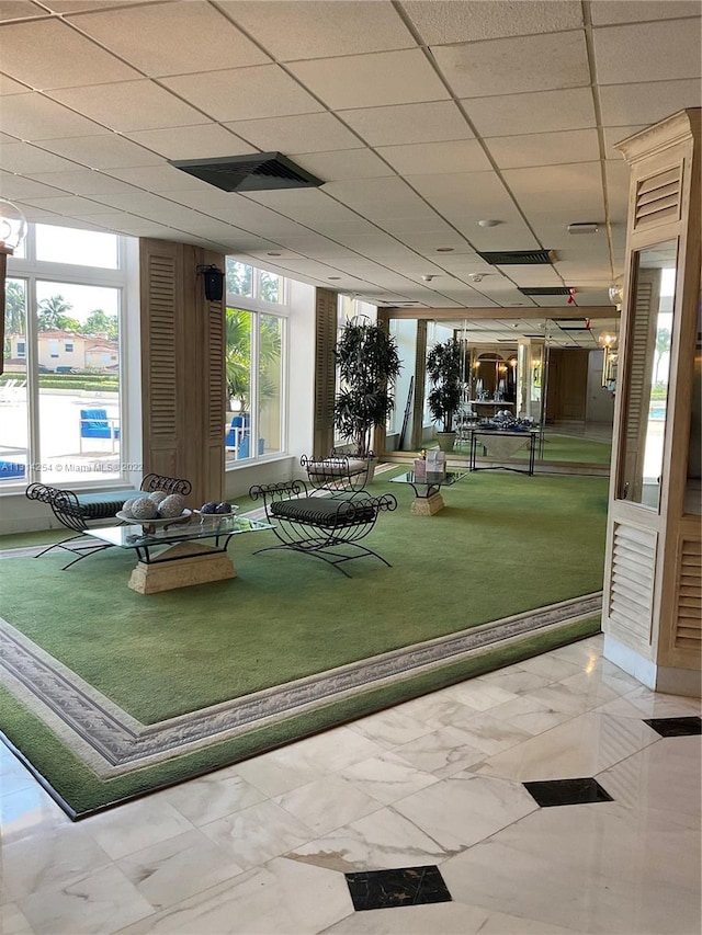 gym with a paneled ceiling and light tile floors