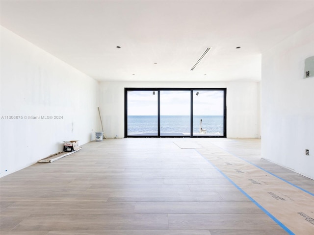 unfurnished room featuring light hardwood / wood-style flooring and a water view