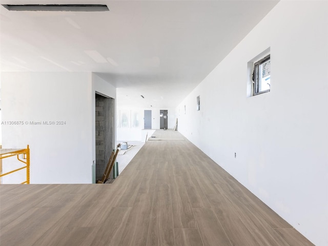 hall with wood-type flooring and a healthy amount of sunlight