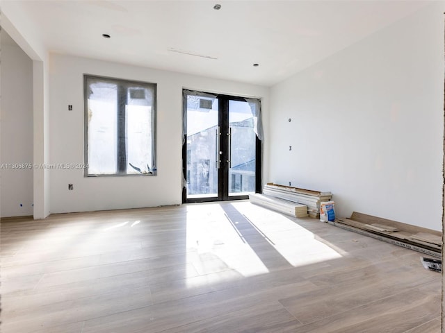 empty room featuring french doors and light hardwood / wood-style flooring