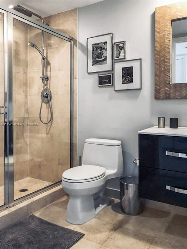 bathroom with toilet, tile floors, an enclosed shower, and vanity