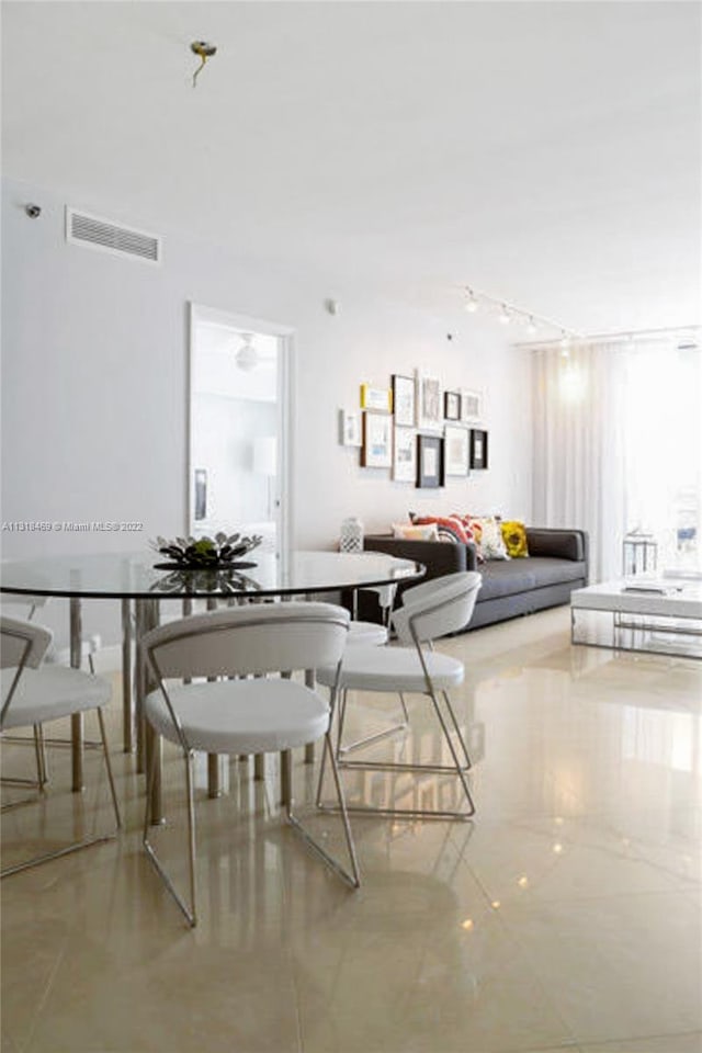 dining room featuring rail lighting and light tile flooring