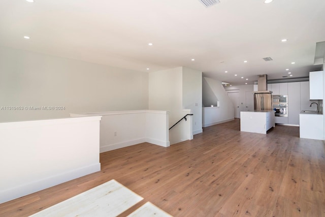 unfurnished living room featuring wood-type flooring and sink