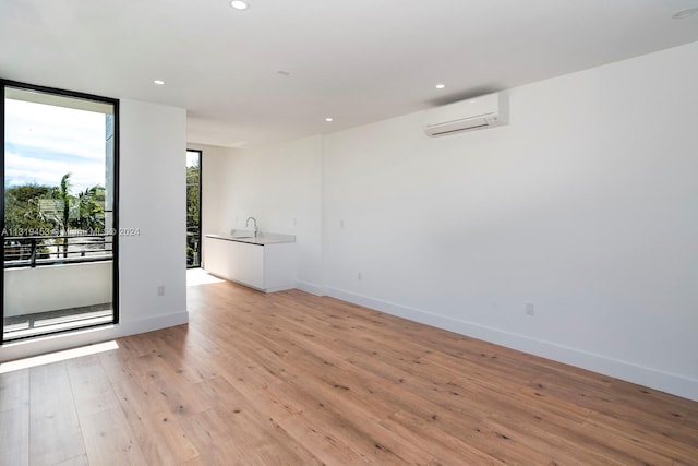 empty room with light hardwood / wood-style floors, sink, and an AC wall unit