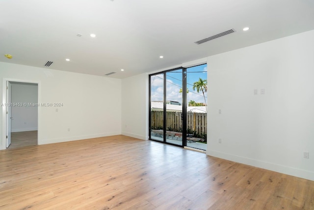 spare room with floor to ceiling windows and light hardwood / wood-style floors