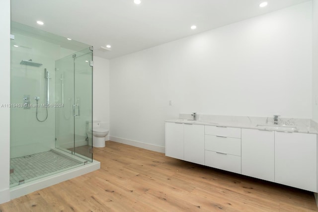 bathroom featuring toilet, double vanity, hardwood / wood-style floors, and an enclosed shower