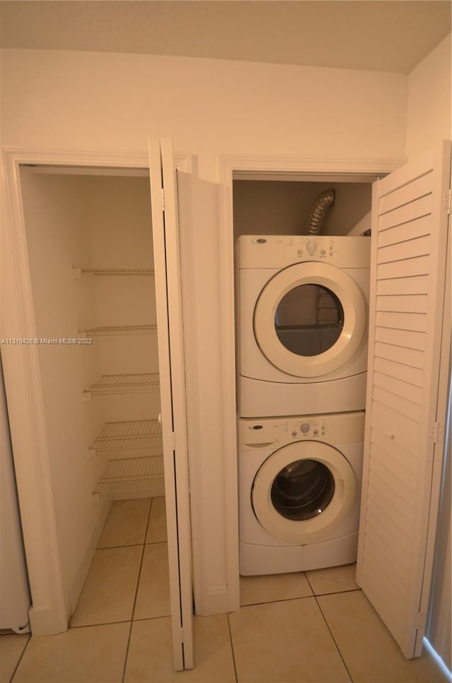 washroom with stacked washer / dryer and light tile patterned flooring