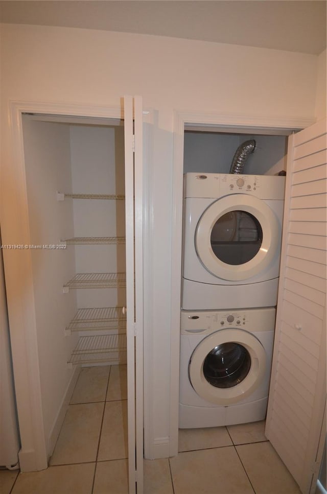 laundry area with light tile patterned flooring and stacked washer and clothes dryer