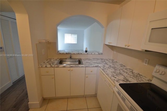 kitchen featuring sink, light tile patterned floors, light stone counters, white appliances, and white cabinets