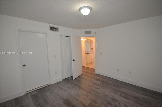 unfurnished bedroom featuring a textured ceiling and dark hardwood / wood-style floors