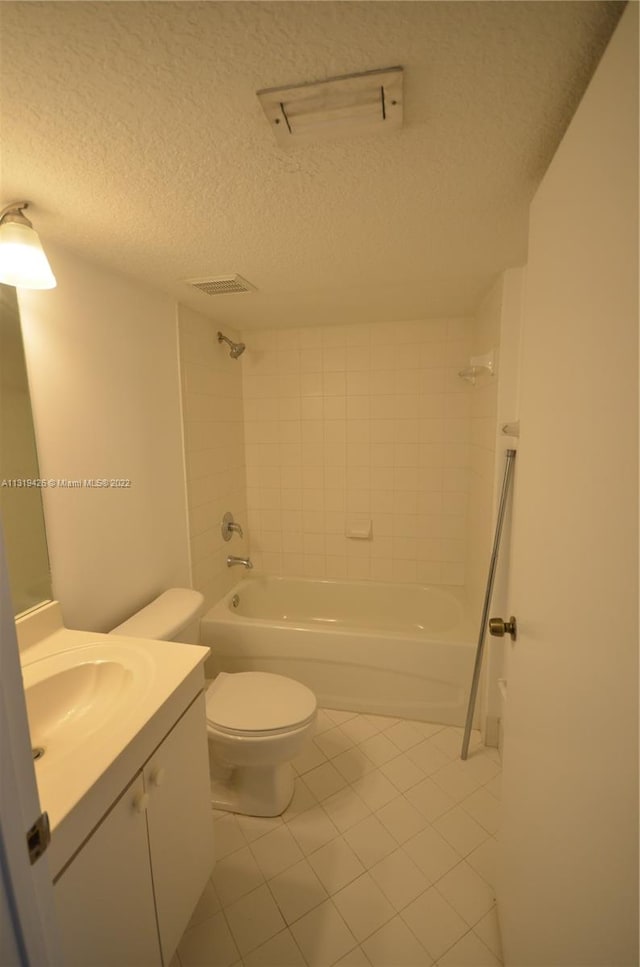 full bathroom featuring tile patterned floors, a textured ceiling, toilet, vanity, and tiled shower / bath