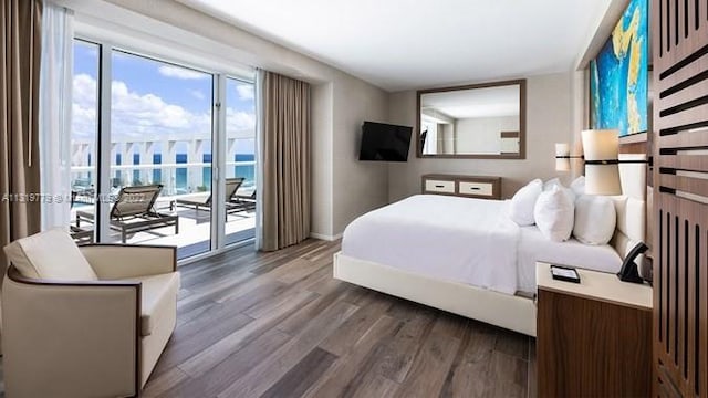 bedroom with hardwood / wood-style floors, access to outside, and a water view