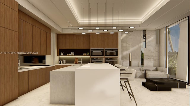 kitchen featuring sink, a tray ceiling, a kitchen breakfast bar, a kitchen island, and expansive windows