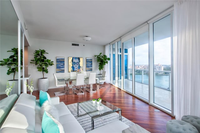 living room with floor to ceiling windows, dark wood-type flooring, and a water view