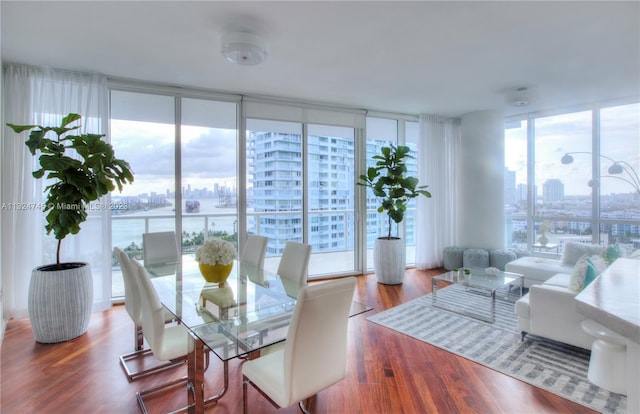 dining area with floor to ceiling windows, hardwood / wood-style flooring, and a water view