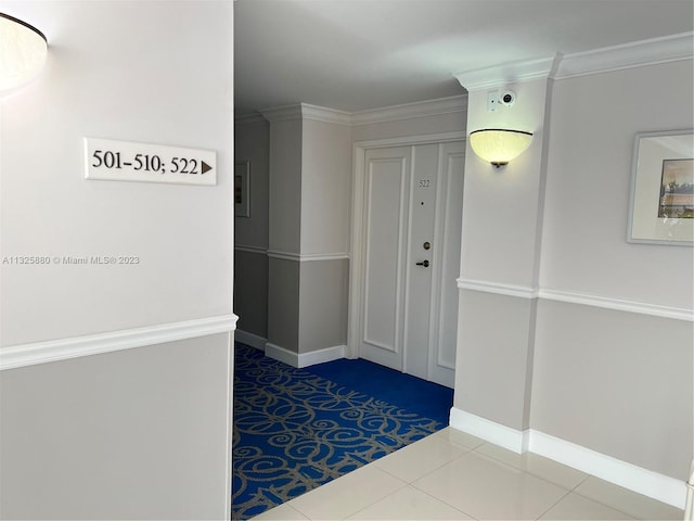 hallway featuring light tile floors and crown molding