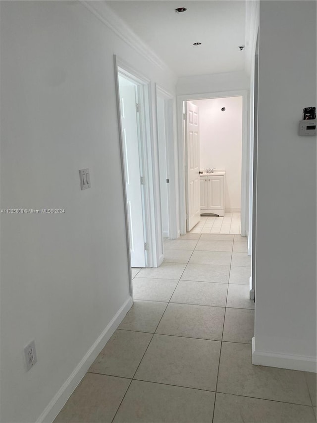 hallway featuring light tile flooring and ornamental molding