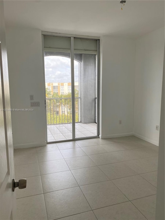 tiled empty room featuring a wall of windows